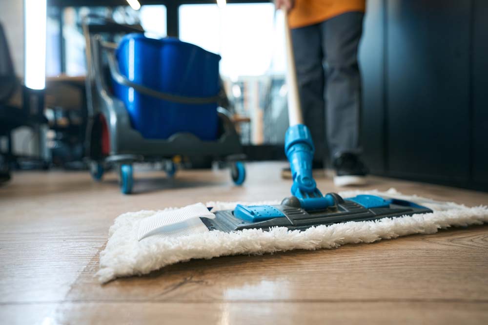 An image of a person cleaning the floor with a mop
